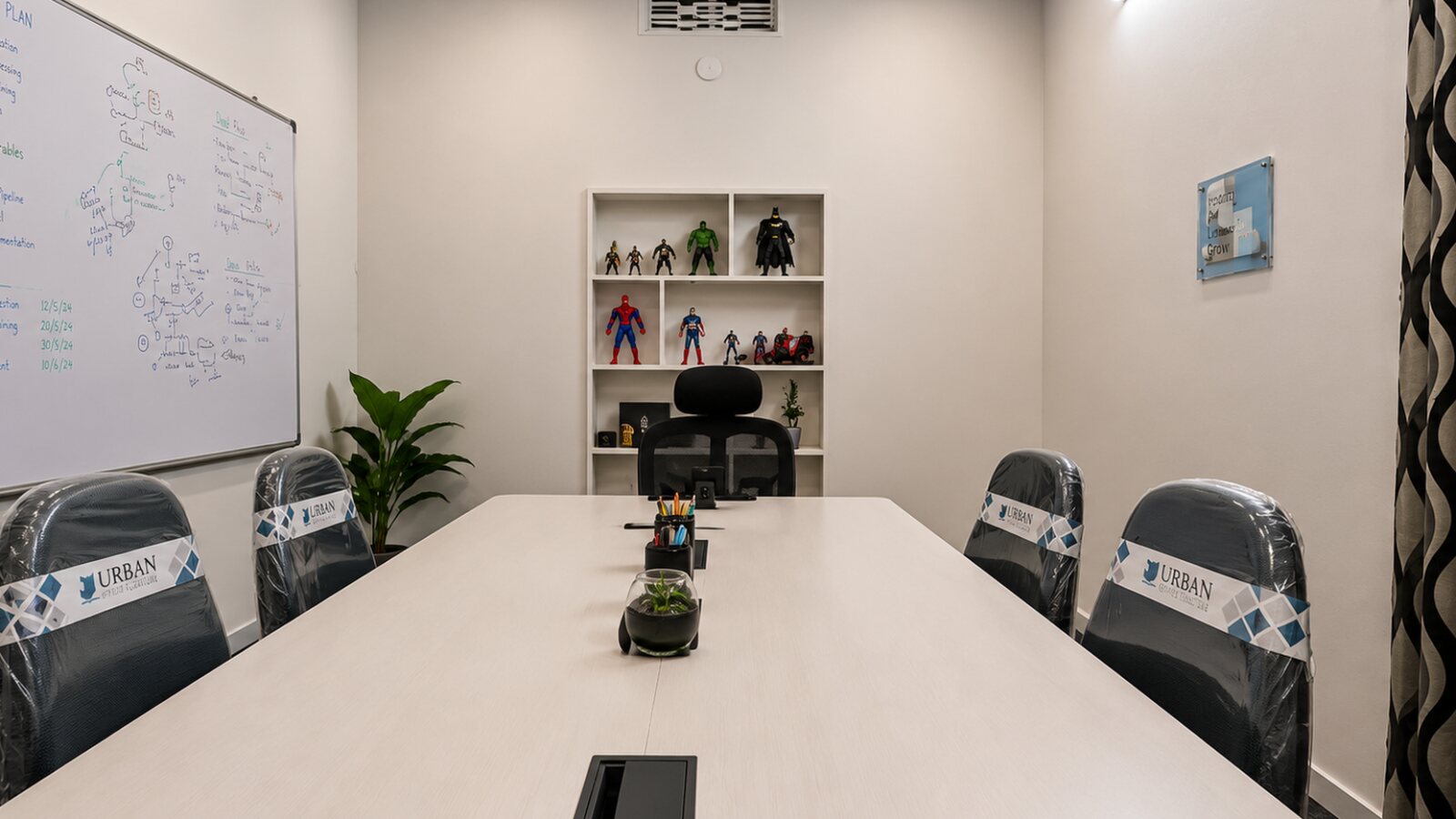 The same boardroom before it opened: an empty table, the factory wrapping still on the chairs and the project plan already on the whiteboard.